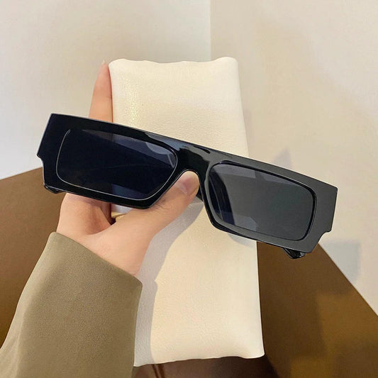 Black rectangular sunglasses held in hand, stylish unisex eyewear for fashion or daily wear