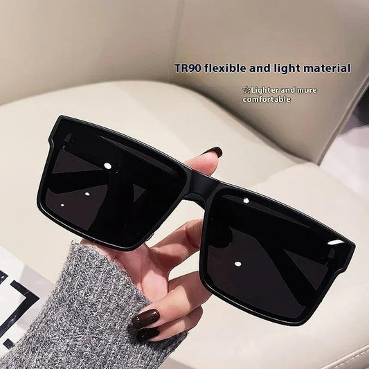 Black oversized square sunglasses with TR90 lightweight frame, held in hand for fashion wear