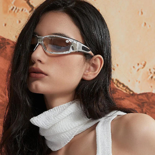 Stylish silver-framed sunglasses with tinted lenses, worn by woman in white knit top against warm-toned backdrop