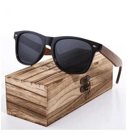 Black wayfarer sunglasses with wooden arms on rustic wood box, stylish men’s and women’s eyewear