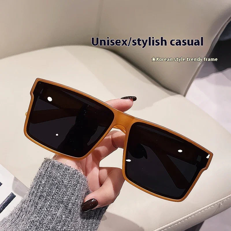 Hand holding unisex stylish casual sunglasses with dark lenses and brown Korean style trendy frame