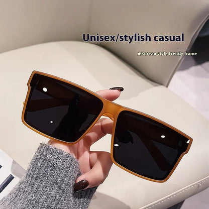 Hand holding unisex stylish casual sunglasses with dark lenses and brown Korean style trendy frame