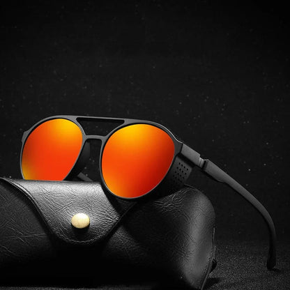 Black aviator sunglasses with orange mirrored lenses resting on black leather case against dark background