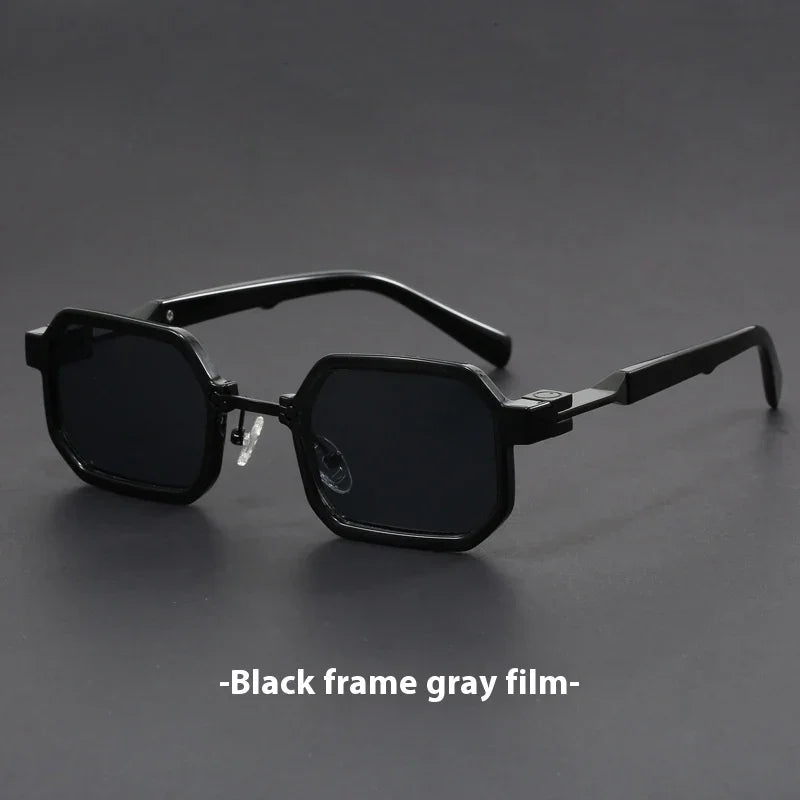 Black geometric frame sunglasses with gray tinted lenses on gray surface
