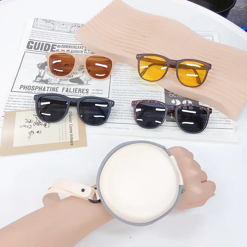 Four pairs of stylish sunglasses with black, tortoiseshell, amber, and yellow lenses displayed on a white table