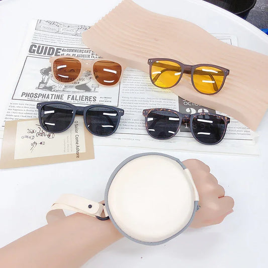 Four pairs of stylish sunglasses with black, tortoiseshell, amber, and yellow lenses displayed on a white table