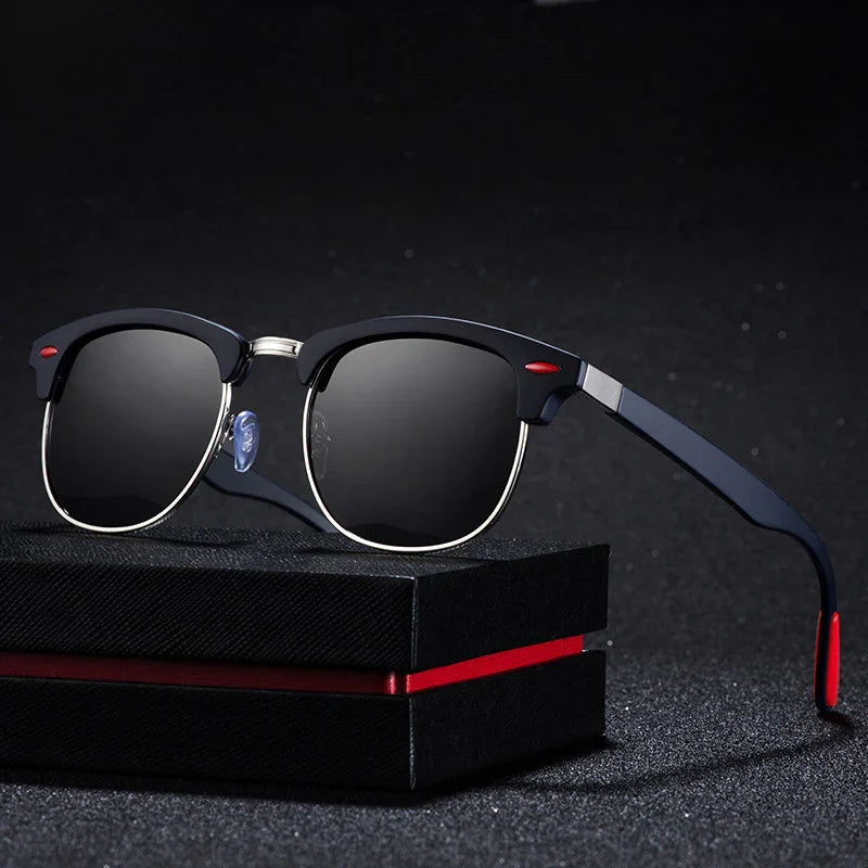 Black and silver sunglasses with dark lenses resting on a textured black box with a red stripe