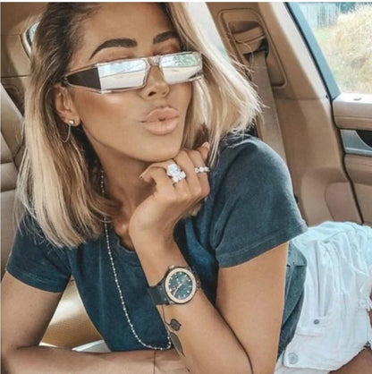 Blonde woman wearing futuristic sunglasses and casual tee, posing inside a car with luxury interior