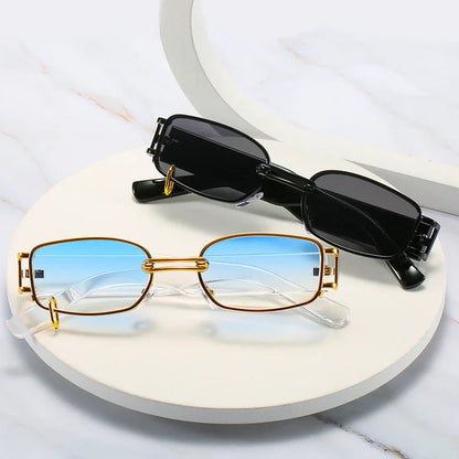 Two pairs of rectangular sunglasses on a white round platform, one with gold frames and blue gradient lenses, the other with black frames and dark lenses