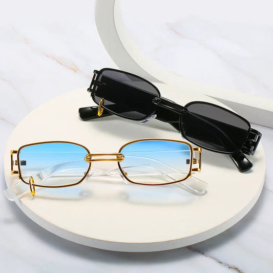 Two pairs of rectangular sunglasses on a white round platform, one with gold frames and blue gradient lenses, the other with black frames and dark lenses