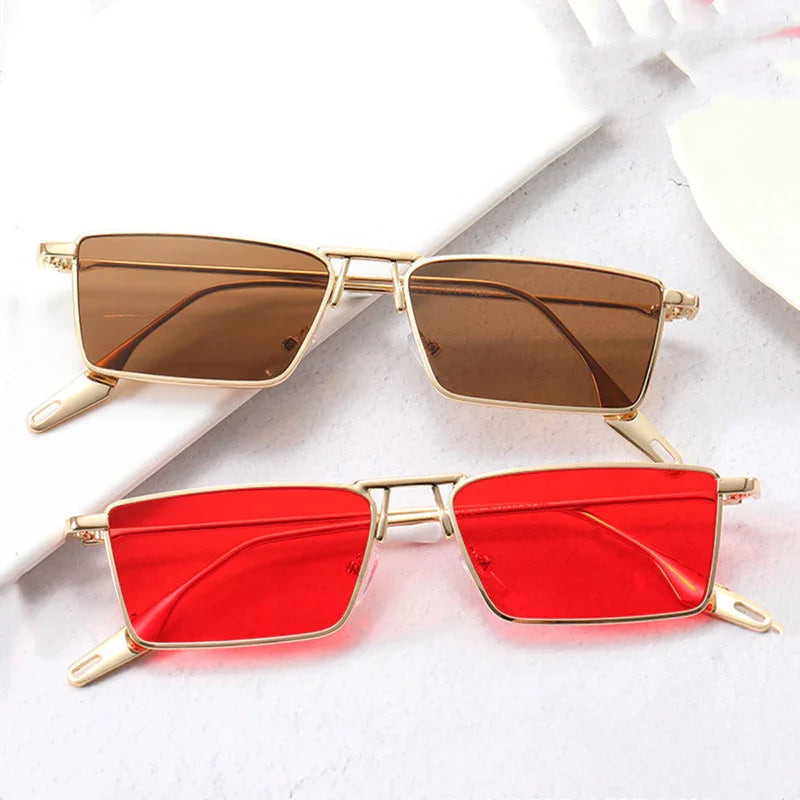 Two rectangular sunglasses with gold metal frames, one with brown lenses and one with red lenses, placed on a white surface