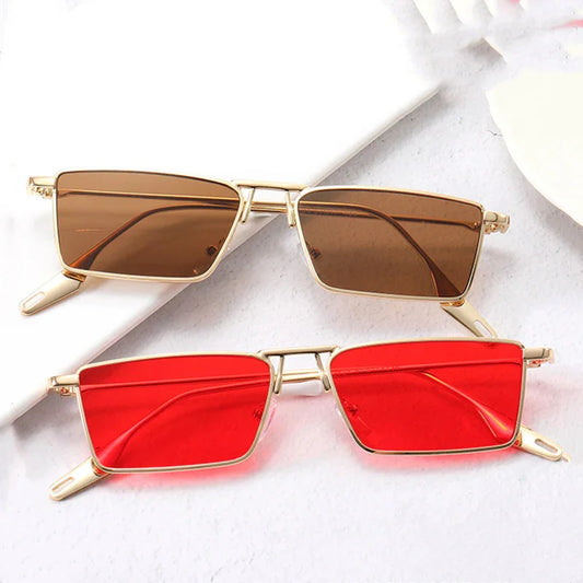 Two rectangular sunglasses with gold metal frames, one with brown lenses and one with red lenses, placed on a white surface