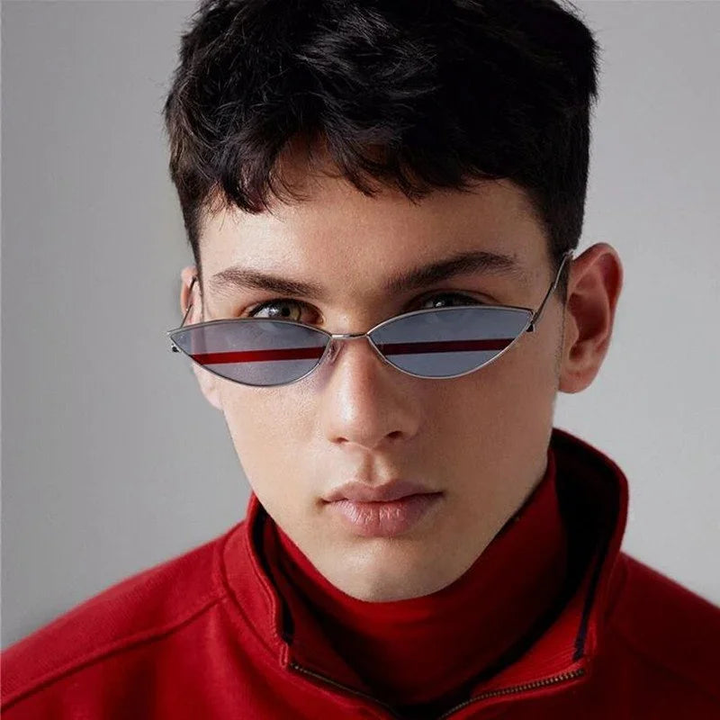 Young man wearing slim cat-eye sunglasses and a red zip-up jacket against gray background