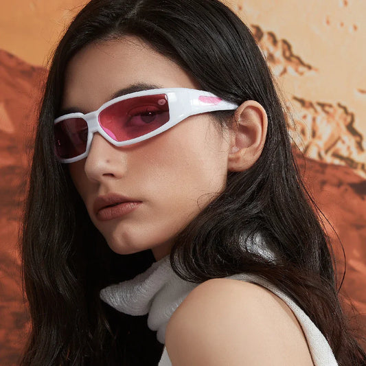 Close-up of woman wearing white futuristic sunglasses with pink lenses against desert background
