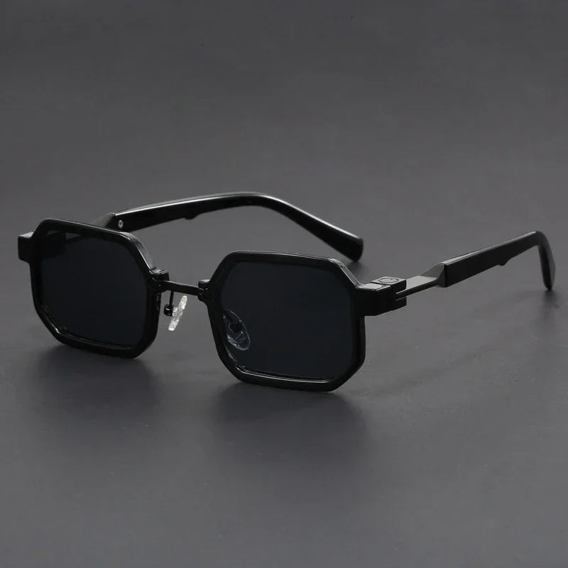 Black hexagonal frame sunglasses with dark lenses on a dark gray surface