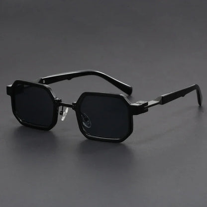 Black hexagonal frame sunglasses with dark lenses on a dark gray surface