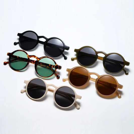 Five pairs of round sunglasses with various colored frames and tinted lenses on white background
