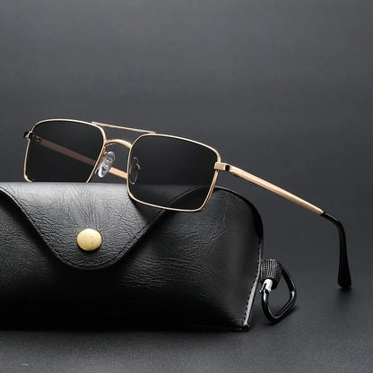 rectangular sunglasses with gold metal frame and black lenses resting on black leather case with gold button
