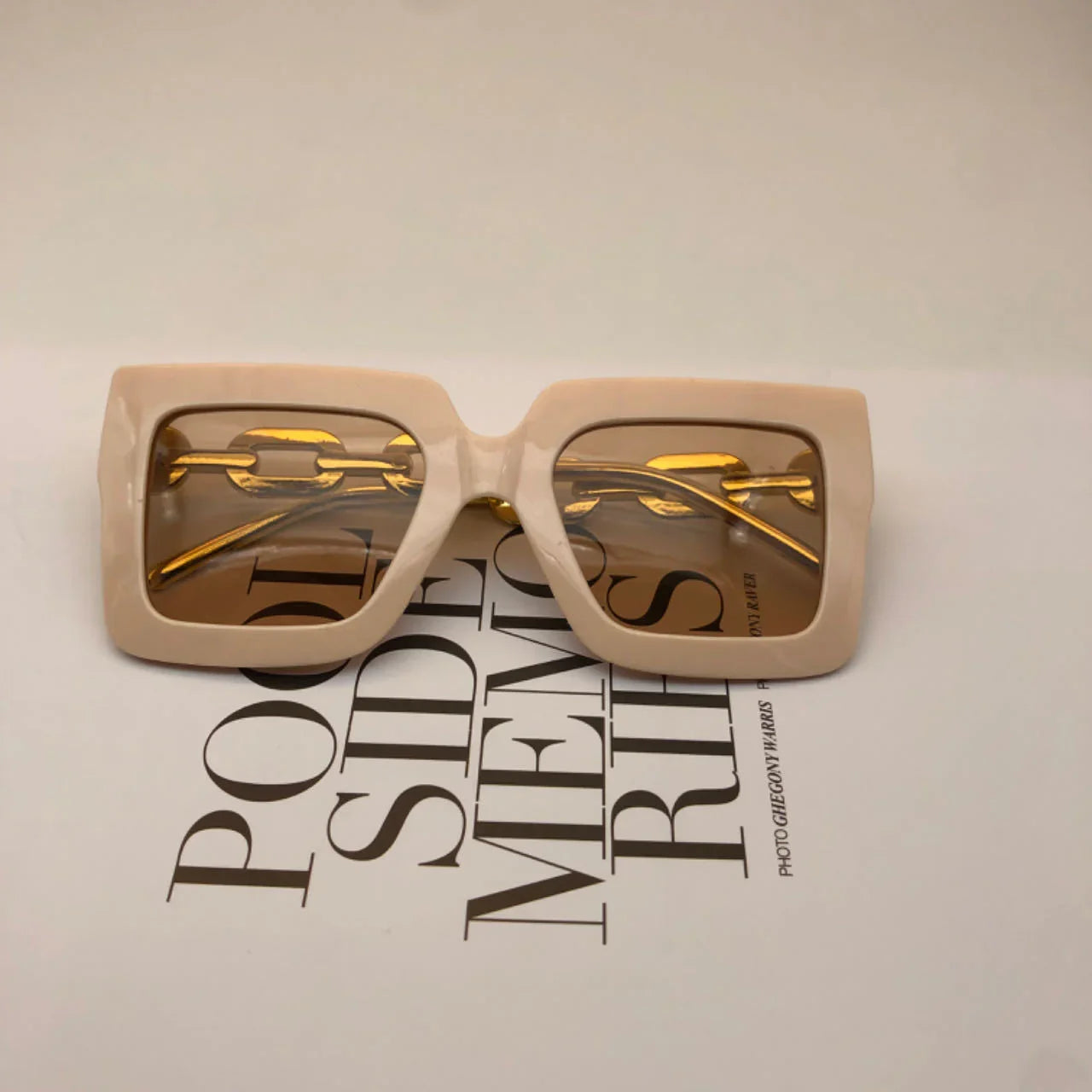 Beige square frame sunglasses with amber lenses on fashion magazine page