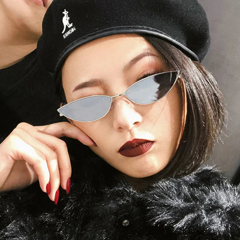 Woman wearing cat-eye sunglasses, black beret, dark red lipstick, and black faux fur coat