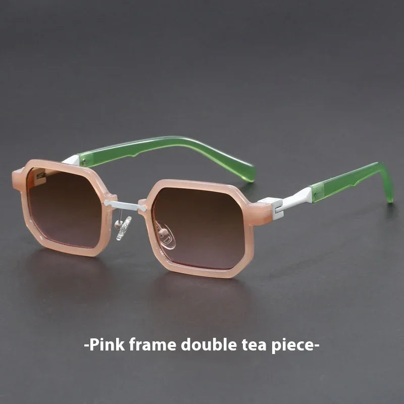 Hexagonal sunglasses with pink translucent frame, green temples, and gradient brown lenses on gray surface