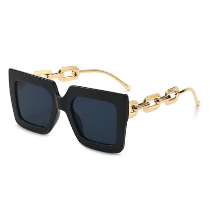 Fashionable oversized square black sunglasses with dark lenses and gold chain-link temples