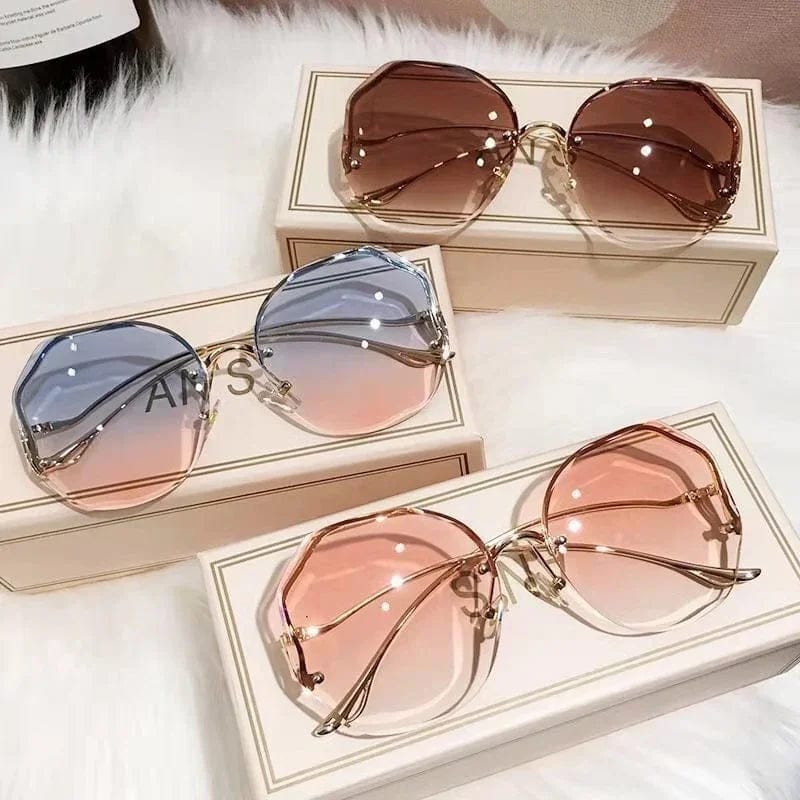 Three pairs of stylish oversized sunglasses with gradient colored lenses on white boxes and a fluffy surface