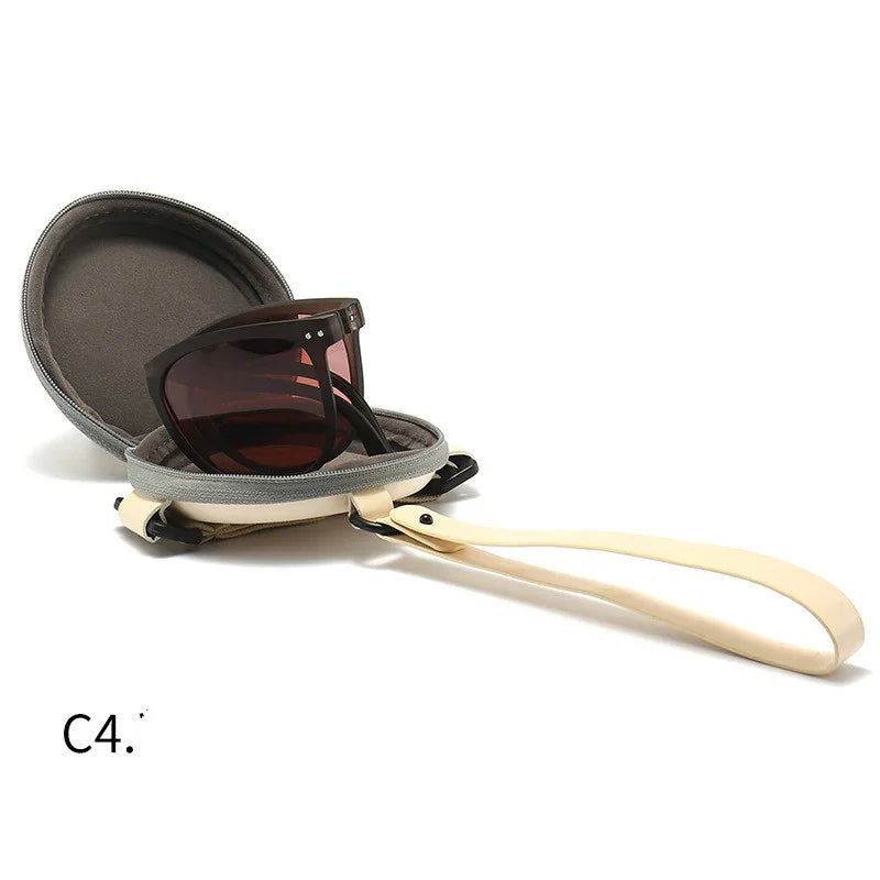 Brown sunglasses in a round gray hard case with beige wrist strap on white background