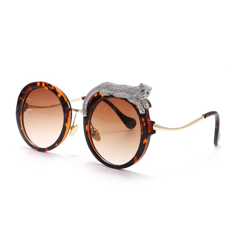 Round tortoiseshell sunglasses with brown gradient lenses and decorative silver leopard detail on frame
