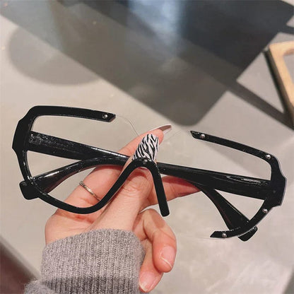 Hand holding black oversized geometric sunglasses with translucent lenses and rhinestone accents