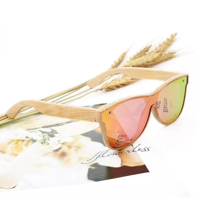 Polarized sunglasses with bamboo frame and pink-green reflective lenses on floral magazine page with wheat stalks