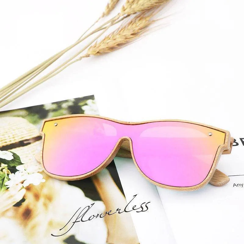 Polarized sunglasses with blue bamboo frame and pink mirrored lenses on magazine with dried wheat