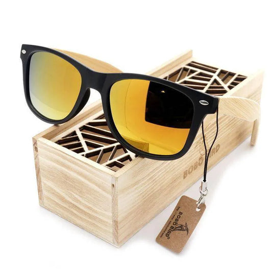 Black frame sunglasses with yellow mirrored lenses and wooden temples resting on a decorative wooden box