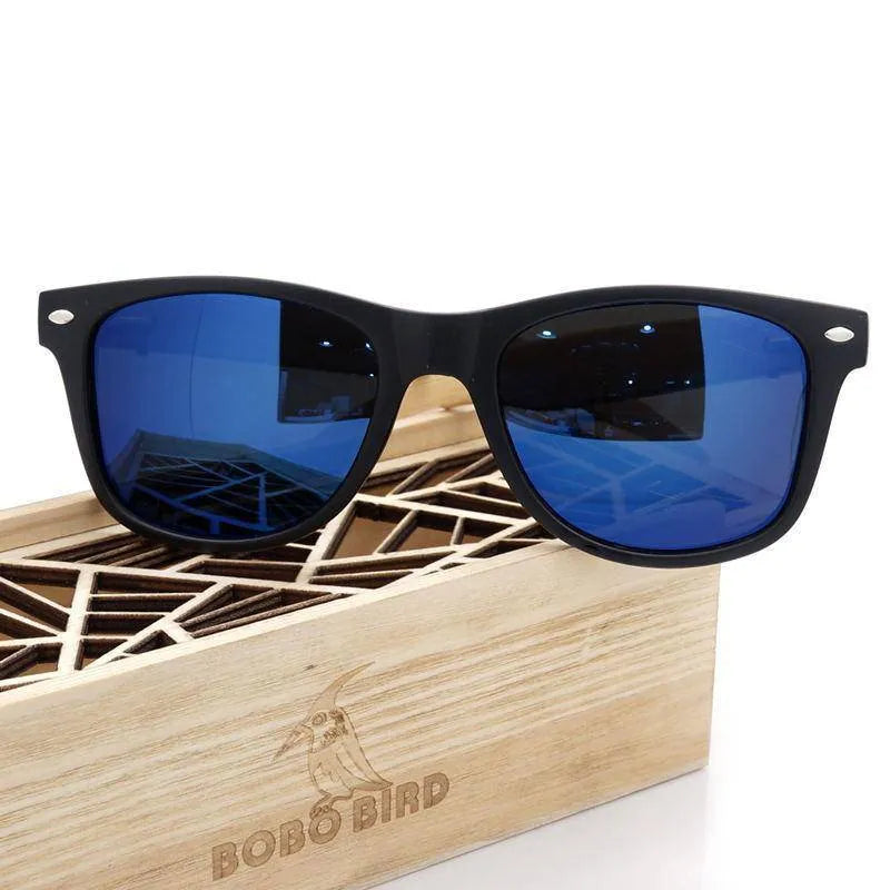 Black frame sunglasses with blue reflective lenses resting on a wooden geometric patterned box