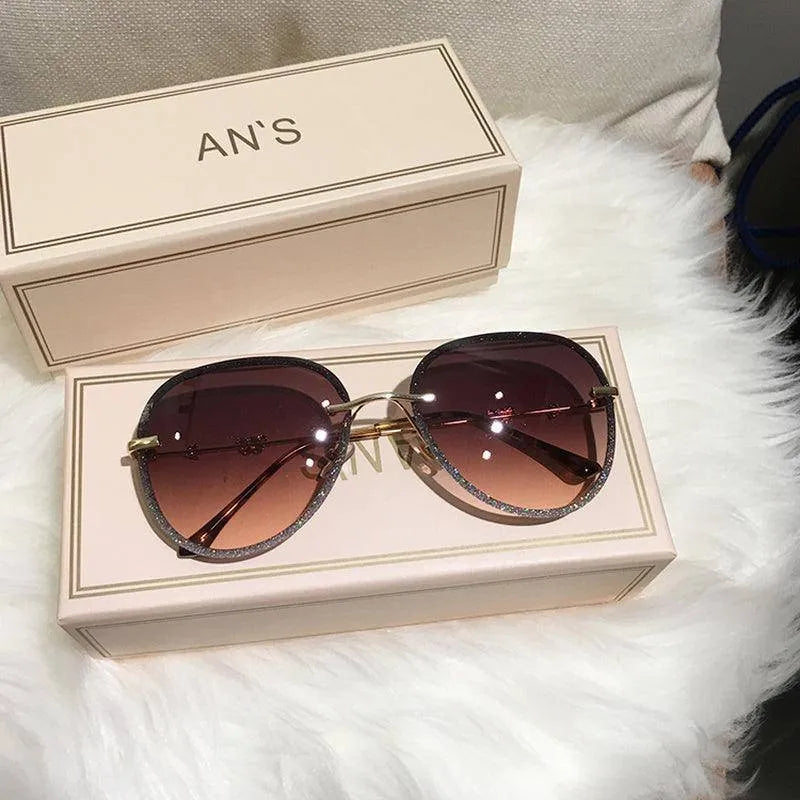 Luxury women's oversized sunglasses with gradient brown lenses and gold frame on beige box