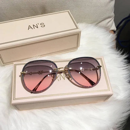 Luxury women's oversized sunglasses with pink gradient lenses on beige box, placed on white fur