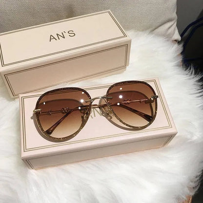 Luxury oversized brown gradient sunglasses with slim metal frame resting on beige textured box on white fur