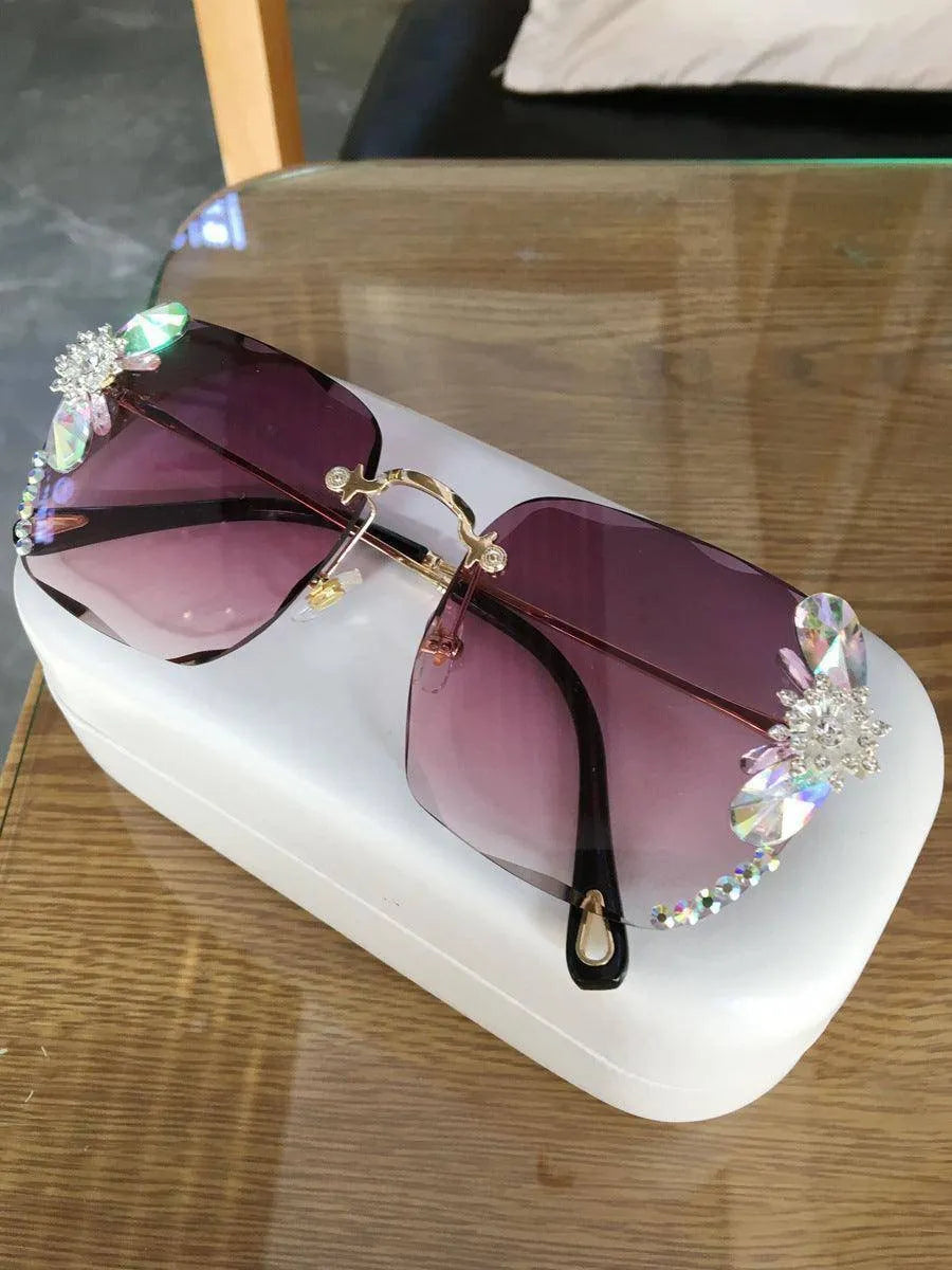Grey frameless rhinestone gradient sunglasses with decorative crystals on a white case