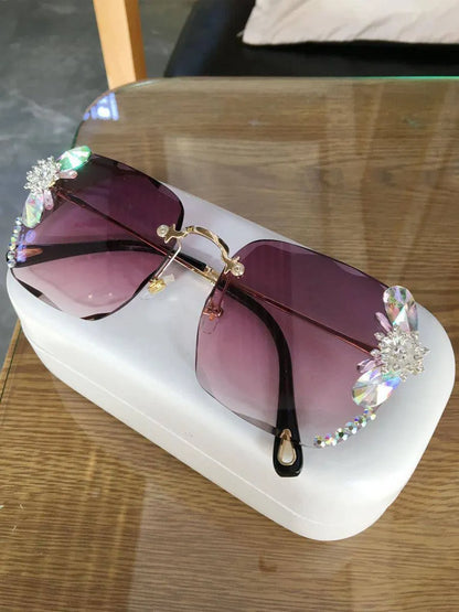 Grey frameless rhinestone gradient sunglasses with decorative crystals on a white case